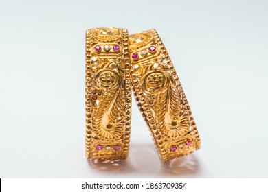 Stylish One Pair Golden Bangle With Small Red Stones Work All Over Isolated On White Background.