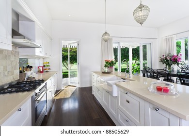 Stylish open plan kitchen with stainless steel appliances and dining area overlooking a pool and golf course - Powered by Shutterstock