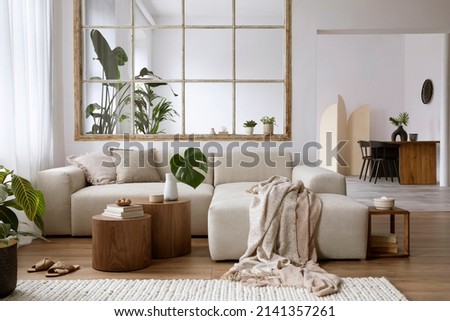 Stylish open space interior with design modular sofa, furniture, coffee tables, plaid, pillows, tropical plants and elegant accessories in elegant home decor. Neutral living room. Template.