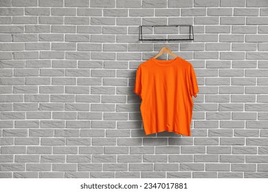 Stylish orange t-shirt hanging on grey brick wall - Powered by Shutterstock