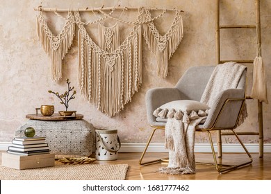 Stylish oriental living room with design armchair, beautiful macrame, big pouf, decoration, carpet, tray and elegant personal accessories in wabi sabi concept. 