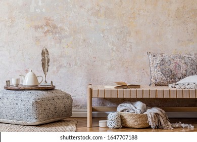 Stylish oriental living room interior with beige chaise longue, rattan decoration, big pouf with wooden tray and tea pot, book and elegant personal accessories. Wabi sabi concept. Copy space. Template