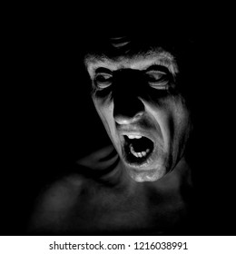 Stylish portrait of adult caucasian man with very angry face and who seems like maniac or devil. He screams at someone. Black and white shot, low-key lighting. Angry man, fear concept.