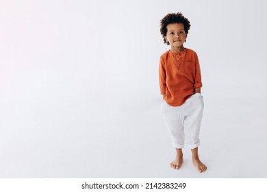 Stylish portrait of a curly dark-skinned 3-year-old boy dressed in stylish linen clothes