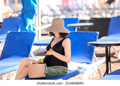 Stylish Pregnant Woman Sitting On Sun Lounge Near Swimming Pool