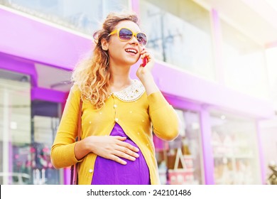 stylish pregnant woman talking on phone