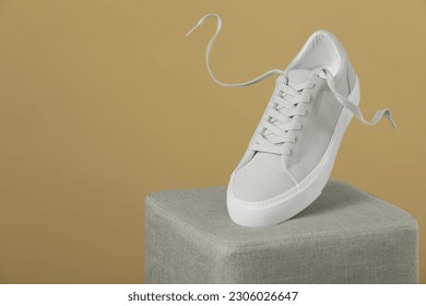 Stylish presentation of trendy sneaker on beige background. Space for text