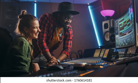 Stylish Producer and Audio Engineer Working together in Music Recording Studio on New Album, Talk, Use Control Desk Equalizer, Mixing Board and Software to Create Hit Song. Artist and Musician Collab - Powered by Shutterstock