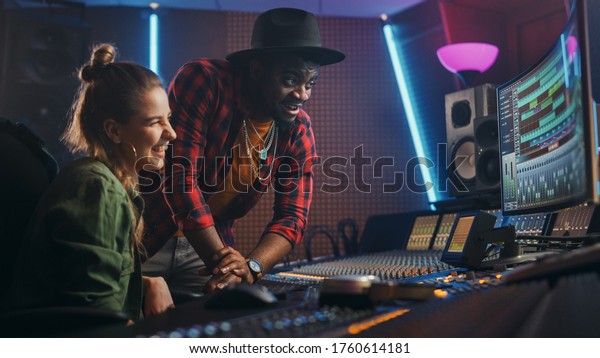 Stylish Producer and Audio Engineer Working\
together in Music Recording Studio on New Album, Talk, Use Control\
Desk Equalizer, Mixing Board and Software to Create Hit Song.\
Artist and Musician\
Collab