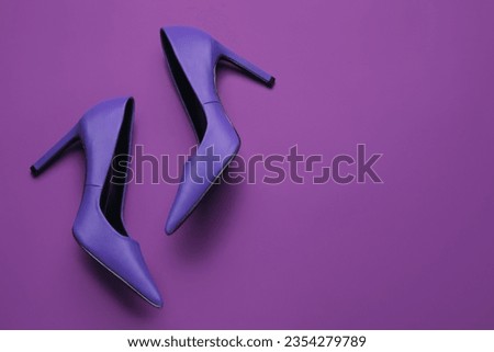 Stylish purple high heels on color background