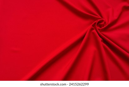 Stylish red fabric with soft curled folds in top right corner and empty space for text. Beautiful background for advertising or design. Flat lay, close-up, top view, copy space, mock up, blank
