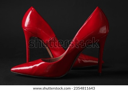 Stylish red high heels on black background