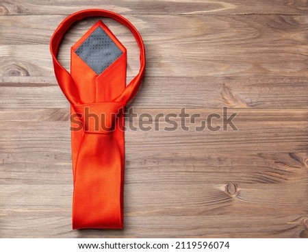 Stylish red necktie on a wooden background with copy space.