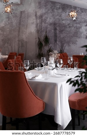 A stylish restaurant setting featuring orange upholstered chairs, white tablecloths, and neatly arranged place settings. Perfect for dining, celebration, or corporate events with upscale ambiance.