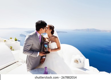 stylish rich asian bride and groom  kissing on the island of Santorini, Greece sunshine