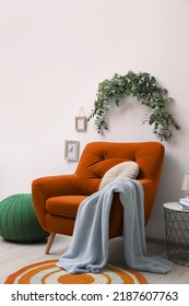 Stylish Room Decorated With Beautiful Eucalyptus Garland Above Comfortable Orange Armchair