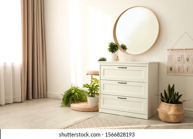 Stylish Room Interior With Chest Of Drawers And Round Mirror