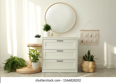 Stylish Room Interior With Chest Of Drawers And Round Mirror