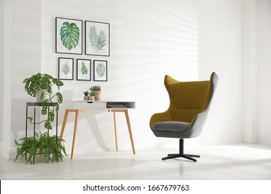 Stylish room interior with comfortable armchair and paintings of tropical leaves - Shutterstock ID 1667679763
