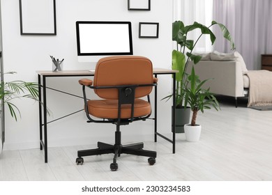 Stylish room interior with comfortable office chair, desk and houseplants - Shutterstock ID 2303234583