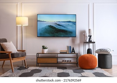 Stylish room interior with modern TV, armchair and decor - Shutterstock ID 2176392569