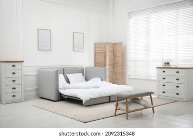Stylish room interior with sleeper sofa near white wall. Additional place for guest - Shutterstock ID 2092315348