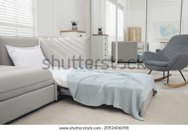 Stylish room interior with sleeper sofa and\
rocking chair. Additional place for\
guest