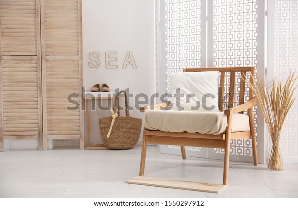 Stylish room interior with white folding screen\
and armchair