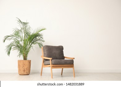 Stylish room interior with wooden armchair and houseplant near light wall. Space for text - Shutterstock ID 1482031889