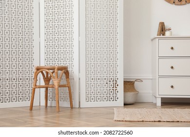 Stylish room with wooden folding screen and chest of drawers near white wall. Interior design - Shutterstock ID 2082722560
