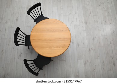 Stylish round table with black chairs on floor, top view. Space for text