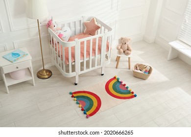 Stylish rug with rainbow on floor in baby room, above view