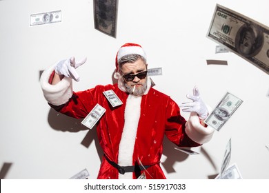 Stylish santa claus in sunglasses smoking and throwing money in the air