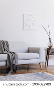 Stylish scandi interior of home space with design grey sofa, retro wooden table, mock up poster frame, decoration , carpet and personal accessories in elegant home decor.