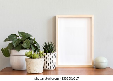 Stylish scandinavian interior with design cabinet, mock up photo frame, elegant accessories and beautiful plants in different pots. Modern home decor. Minimalistic concept. Template. Blank.