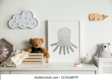 Stylish scandinavian newborn baby room with toys, teddy bears, wooden boxes and cloud. Modern interior with mock up photo frame.