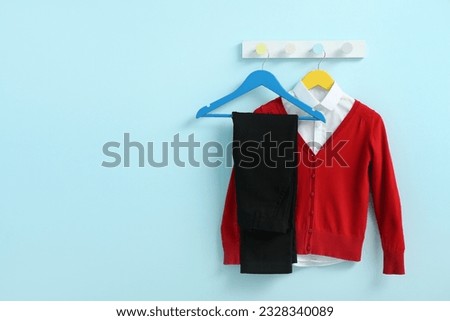 Stylish school uniform hanging on rack against blue wall