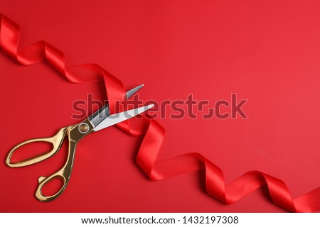 Stylish scissors and red ribbon on color background, flat lay with space for text. Ceremonial tape cutting