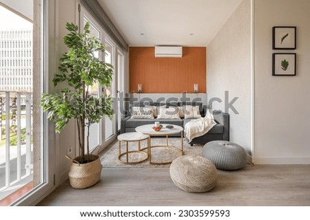 Stylish seating area with a terracotta color wall with a sofa and pouffes near the panoramic windows in the living room. The concept of a modern Scandinavian interior