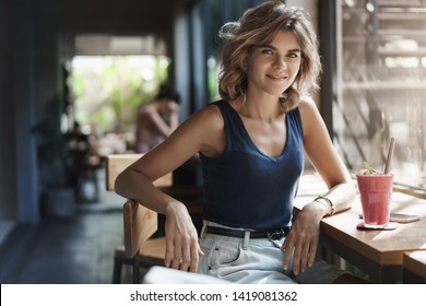 Stylish self-assured charming modern young woman sit trendy urban space cafe lean table bar near window smiling turn camera sassy drink healthy smoothie finish talking smartphone - Shutterstock ID 1419081362