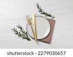 Stylish setting with cutlery and eucalyptus leaves on white marble table, flat lay