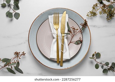 Stylish setting with cutlery and eucalyptus leaves on white marble table, flat lay - Powered by Shutterstock