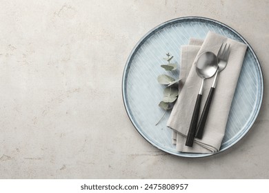 Stylish setting with cutlery, napkin, eucalyptus branch and plate on light grey table, top view. Space for text - Powered by Shutterstock