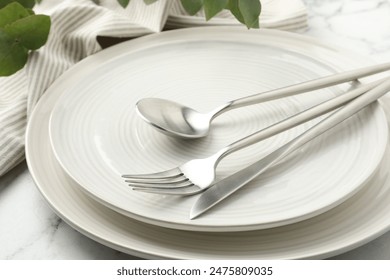 Stylish setting with cutlery, napkin, eucalyptus branches and plates on white marble table, closeup - Powered by Shutterstock