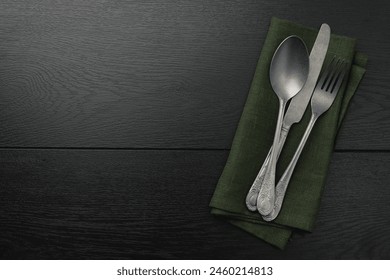 Stylish setting with cutlery and napkin on black wooden table, top view. Space for text - Powered by Shutterstock