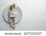 Stylish setting with cutlery, napkin and plates on white table, top view. Space for text