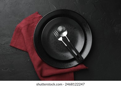 Stylish setting with cutlery, napkin and plates on dark textured table, top view - Powered by Shutterstock