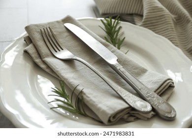 Stylish setting with cutlery, napkin, rosemary and plate on table, closeup - Powered by Shutterstock