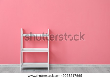 Stylish shelf unit near color wall