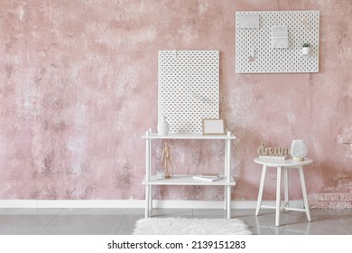 Stylish Shelf Unit With Peg Board On Pink Textured Wall Background